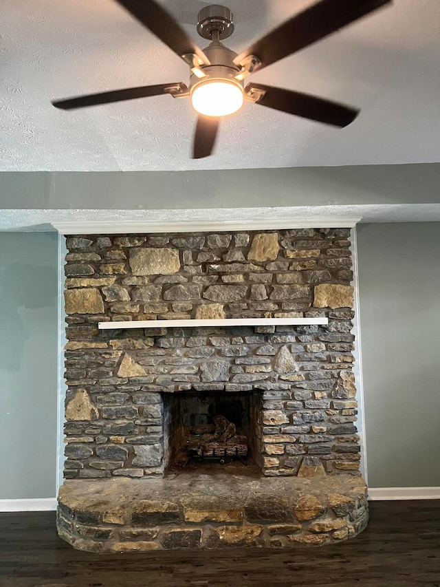 room details featuring ceiling fan, a textured ceiling, wood-type flooring, and a stone fireplace