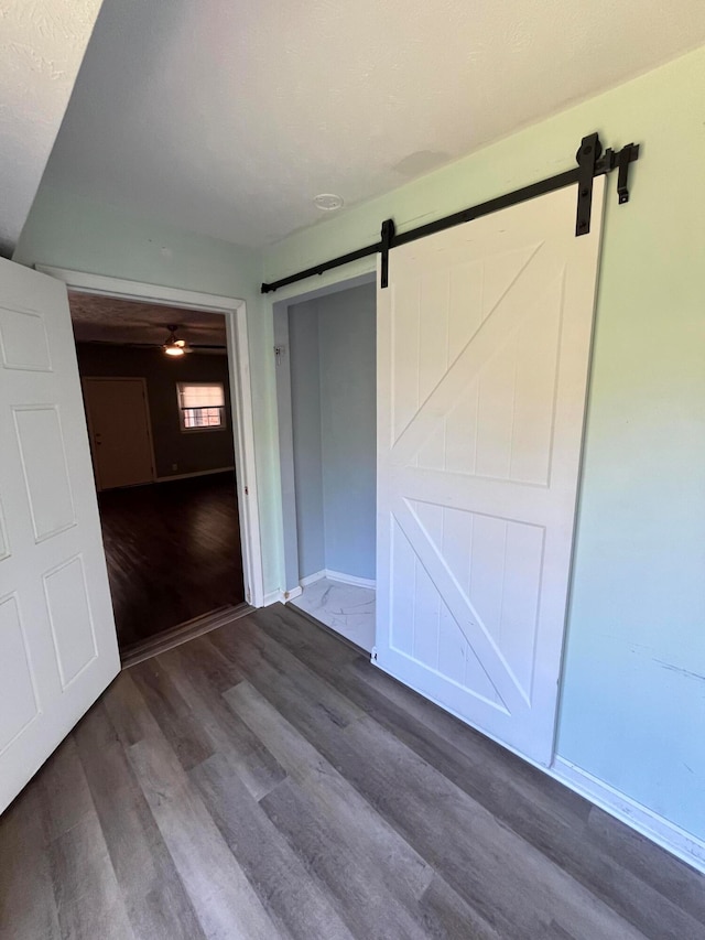 unfurnished bedroom with a barn door and dark hardwood / wood-style flooring