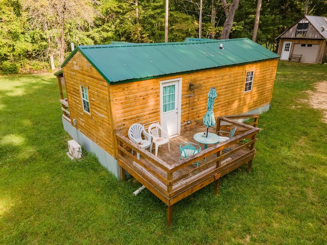 rear view of property featuring a wooden deck, an outbuilding, and a yard