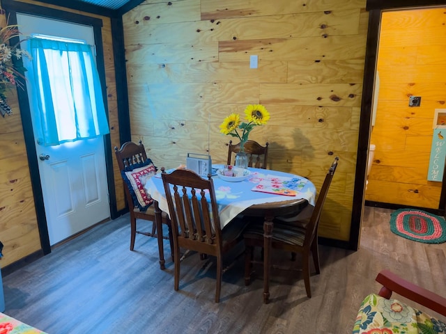 dining area with hardwood / wood-style flooring and wooden walls