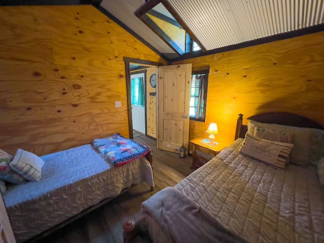 bedroom with vaulted ceiling with skylight, hardwood / wood-style floors, and wooden walls