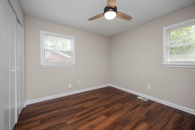 empty room featuring ceiling fan, plenty of natural light, and dark hardwood / wood-style floors