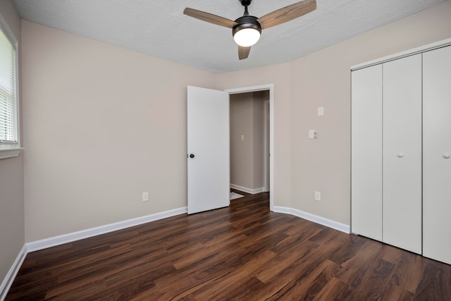 unfurnished bedroom featuring dark wood-type flooring, a closet, ceiling fan, and a textured ceiling