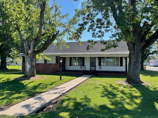 ranch-style home with covered porch and a front lawn