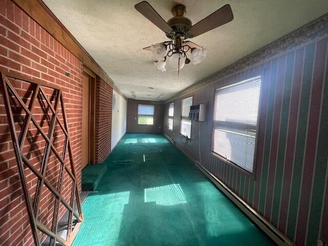 hall with a textured ceiling, brick wall, and carpet floors