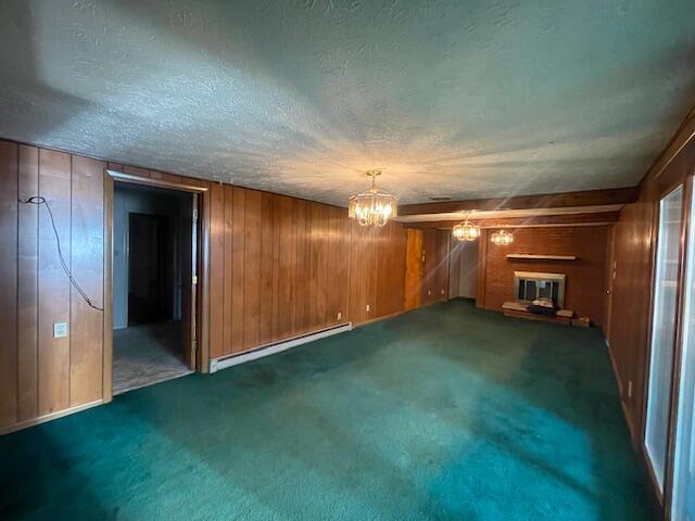 interior space with a textured ceiling, baseboard heating, and wood walls