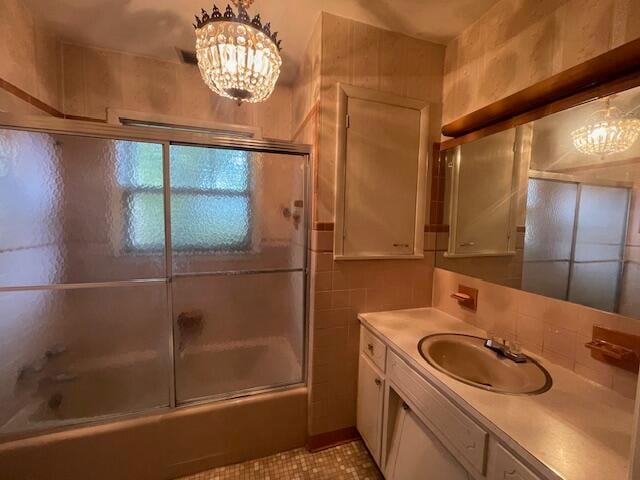 bathroom featuring tile patterned floors, tile walls, enclosed tub / shower combo, and vanity