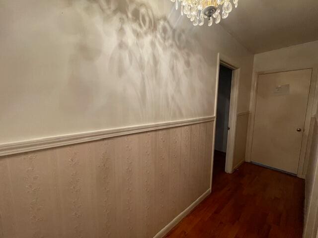 corridor with wood walls, a chandelier, and hardwood / wood-style flooring