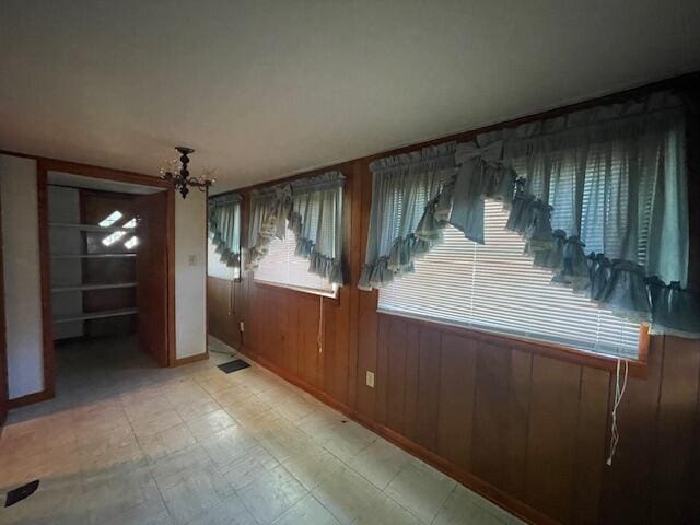 unfurnished room with wood walls and an inviting chandelier