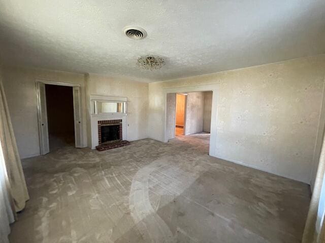 unfurnished living room featuring a textured ceiling and a brick fireplace