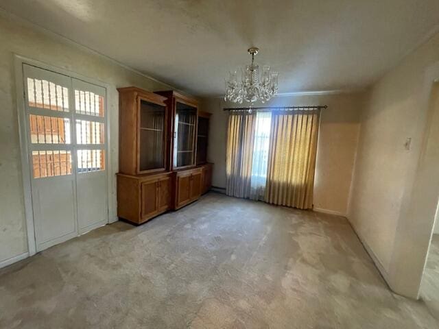 carpeted empty room with an inviting chandelier