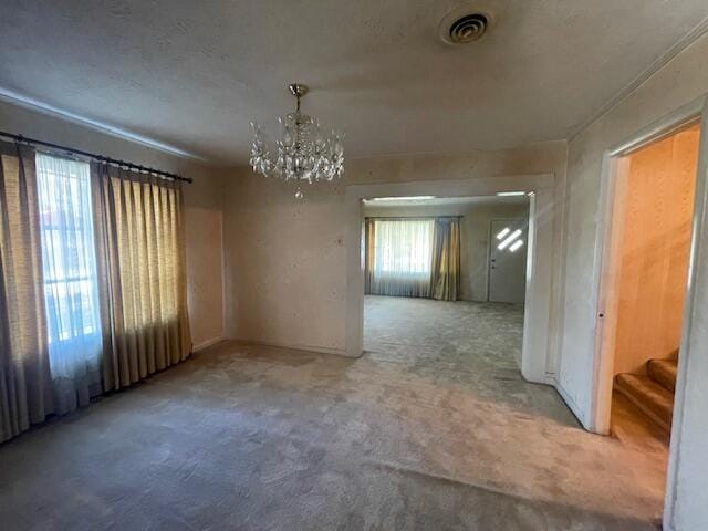 carpeted spare room featuring an inviting chandelier