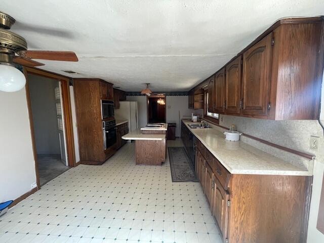 kitchen with white fridge, a kitchen island, sink, ceiling fan, and black oven