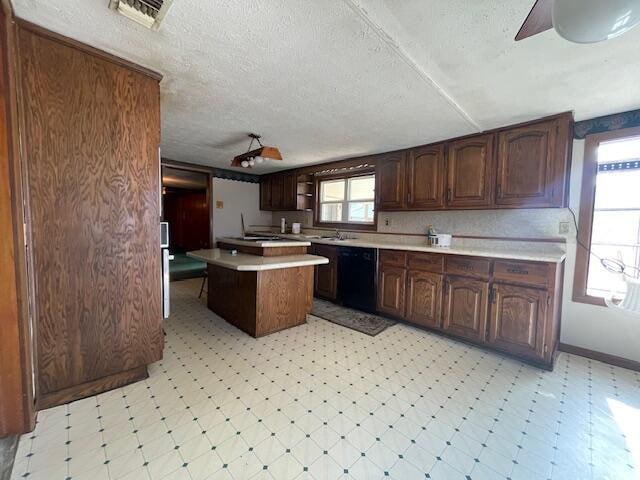 kitchen featuring a kitchen island, dark brown cabinets, a textured ceiling, and black dishwasher