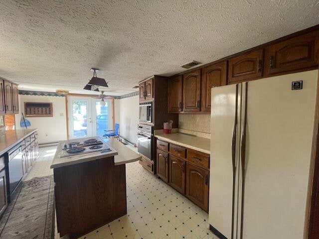 kitchen with a center island, stainless steel appliances, dark brown cabinets, and a textured ceiling