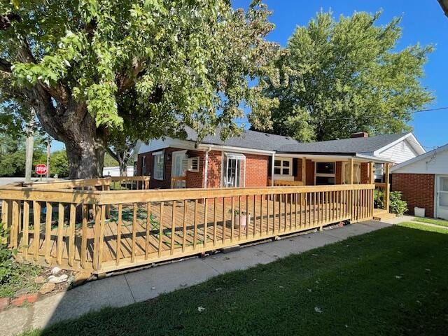 back of property with a wooden deck and a lawn