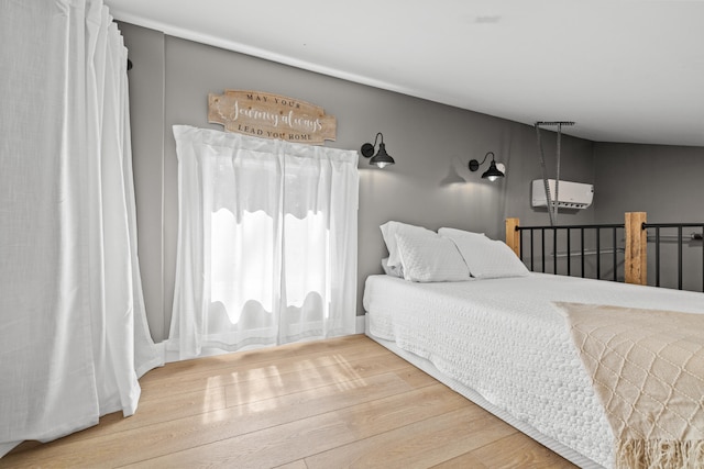 bedroom featuring light hardwood / wood-style flooring and a wall mounted air conditioner