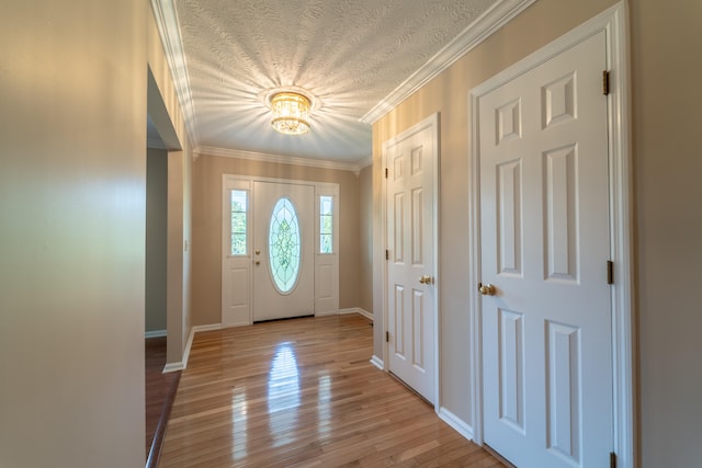 entrance foyer featuring ornamental molding, a textured ceiling, and light hardwood / wood-style flooring