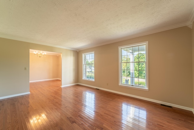 unfurnished room with a textured ceiling, a wealth of natural light, and hardwood / wood-style floors