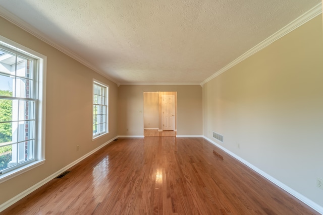 empty room with hardwood / wood-style flooring, ornamental molding, and a textured ceiling