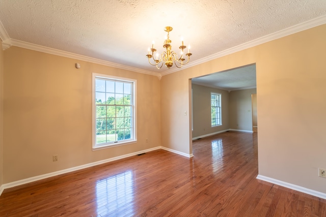 spare room with ornamental molding, a textured ceiling, an inviting chandelier, and dark hardwood / wood-style floors