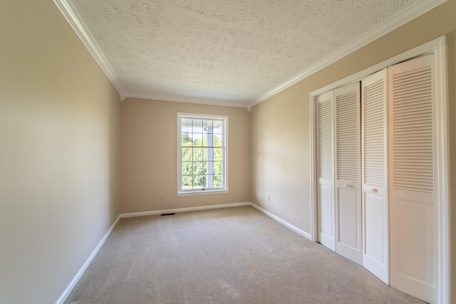 unfurnished bedroom featuring a closet, ornamental molding, a textured ceiling, and carpet floors