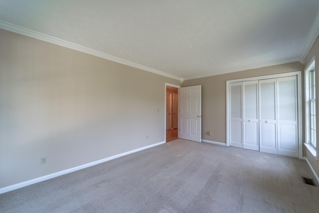 unfurnished bedroom with ornamental molding, carpet floors, and a closet