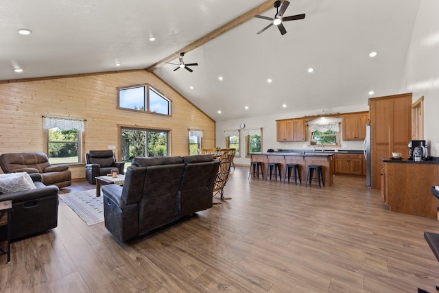 living room featuring high vaulted ceiling, a wealth of natural light, beamed ceiling, and light wood finished floors