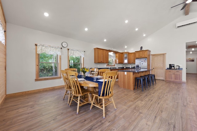 dining area featuring high vaulted ceiling, light wood-style flooring, baseboards, and a wall mounted AC