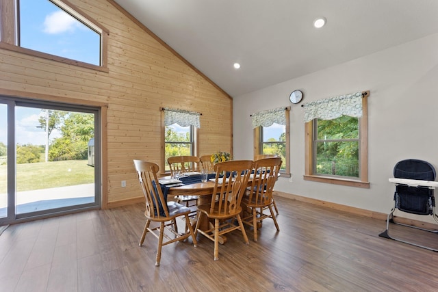 dining room with wood walls, high vaulted ceiling, wood finished floors, and recessed lighting