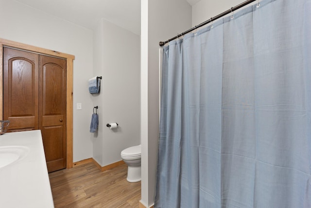 full bathroom featuring wood finished floors, toilet, and baseboards