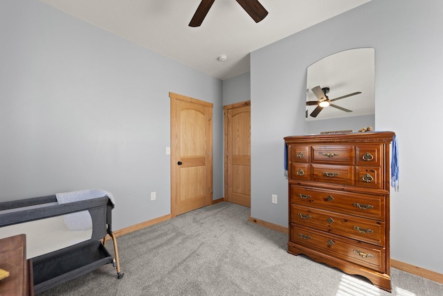 bedroom with a ceiling fan, light carpet, and baseboards