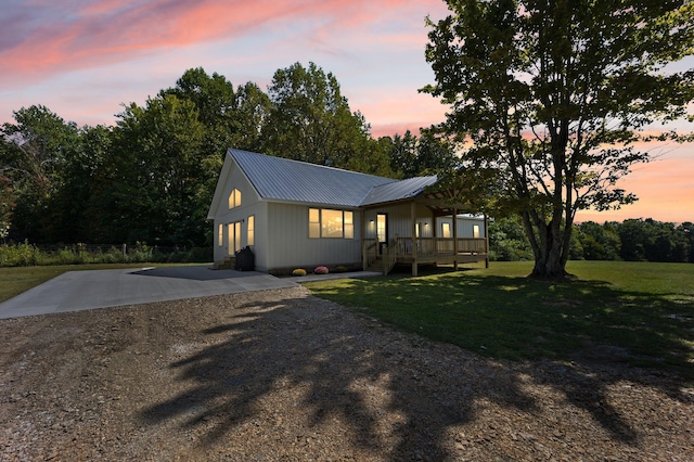 view of front of property featuring metal roof, driveway, a porch, and a front yard