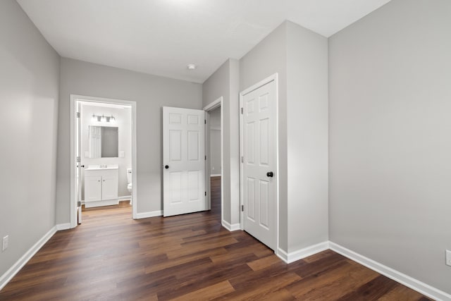 unfurnished bedroom featuring dark wood-type flooring and ensuite bath