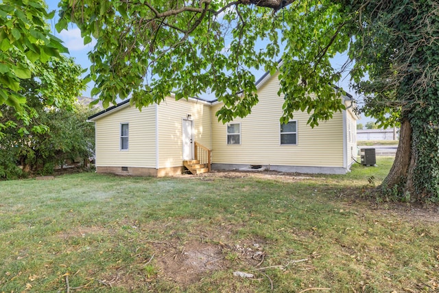 rear view of property featuring central AC unit and a lawn