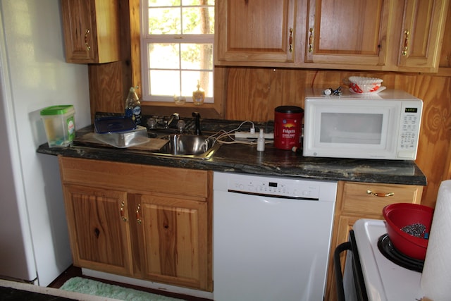 kitchen featuring sink, white appliances, and wooden walls