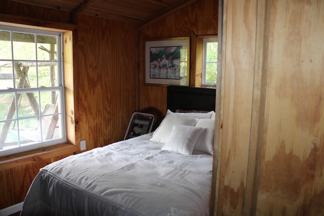 bedroom featuring multiple windows, wood ceiling, wooden walls, and vaulted ceiling