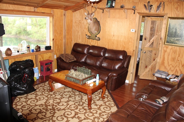 living room with wood walls, hardwood / wood-style floors, and beam ceiling