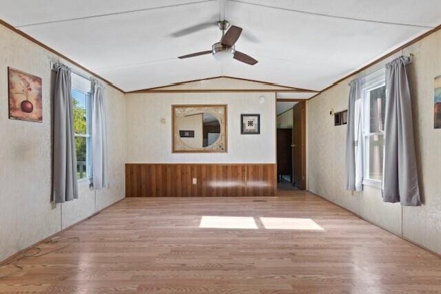 unfurnished room featuring ceiling fan, ornamental molding, light wood-type flooring, and vaulted ceiling