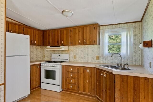 kitchen featuring light hardwood / wood-style flooring, white appliances, vaulted ceiling, and sink