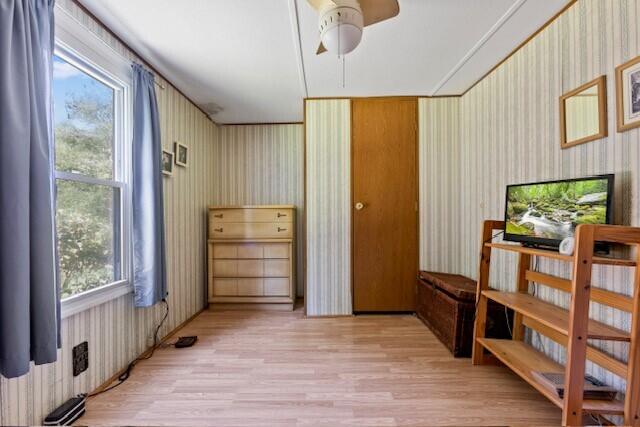 interior space featuring light wood-type flooring, radiator, and ceiling fan