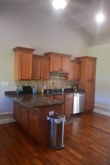 kitchen with dishwasher, ceiling fan, dark stone counters, and dark hardwood / wood-style flooring