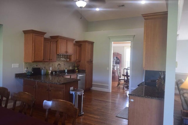 kitchen featuring stainless steel dishwasher, dark stone countertops, ceiling fan, and dark hardwood / wood-style flooring