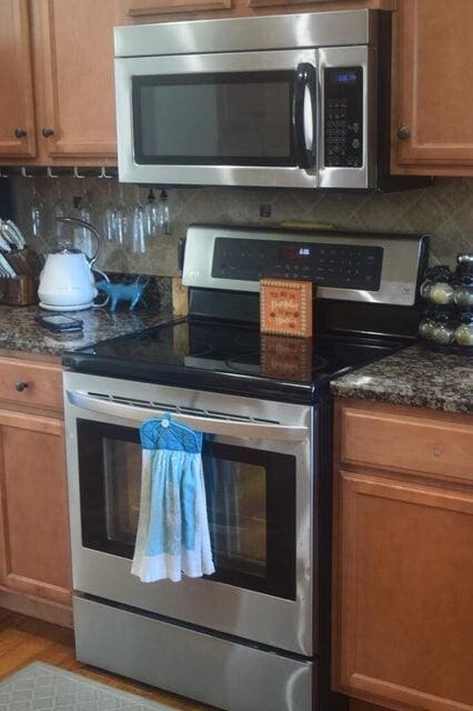 kitchen featuring dark stone countertops, light wood-type flooring, appliances with stainless steel finishes, and tasteful backsplash