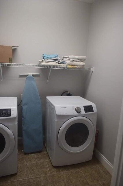 laundry area featuring washing machine and clothes dryer and dark tile patterned floors