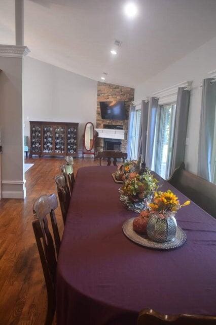 dining room with lofted ceiling, hardwood / wood-style flooring, and a fireplace