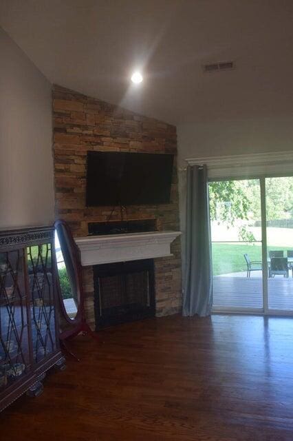 unfurnished living room featuring lofted ceiling, dark wood-type flooring, a wealth of natural light, and a fireplace