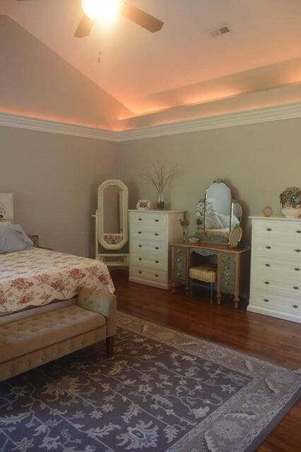 bedroom with lofted ceiling, ceiling fan, wood-type flooring, and a tray ceiling