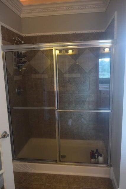 bathroom with ornamental molding, an enclosed shower, and tile patterned floors