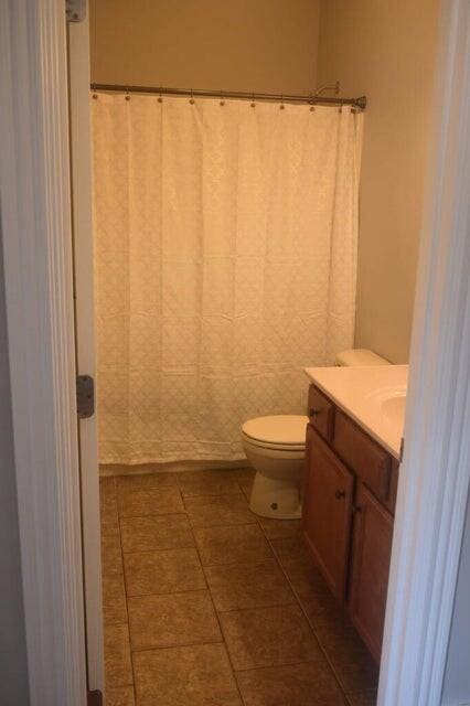 bathroom with curtained shower, tile patterned flooring, toilet, and vanity